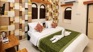 A hotel room with a bed, a wooden table, a ceiling fan, and an air conditioning unit.