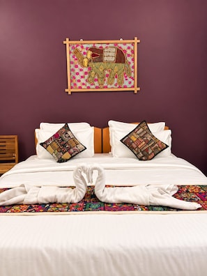 A hotel room with a bed, pillows, a wall hanging, and a towel arrangement. - Hotel Alexa Palace (Jaisalmer)