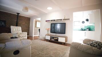 A living room with a flat-screen TV, two sofas, a coffee table, and a patterned rug.