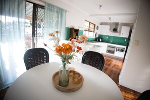 Een eettafel met een bloemenvaas, twee stoelen en een houten onderzetter.