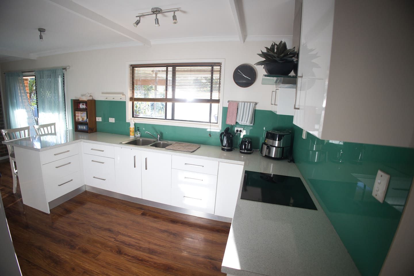 A kitchen with white cabinets, a sink, a coffee maker, and a clock on the wall.