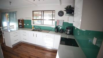 A kitchen with white cabinets, a sink, a coffee maker, and a clock on the wall.