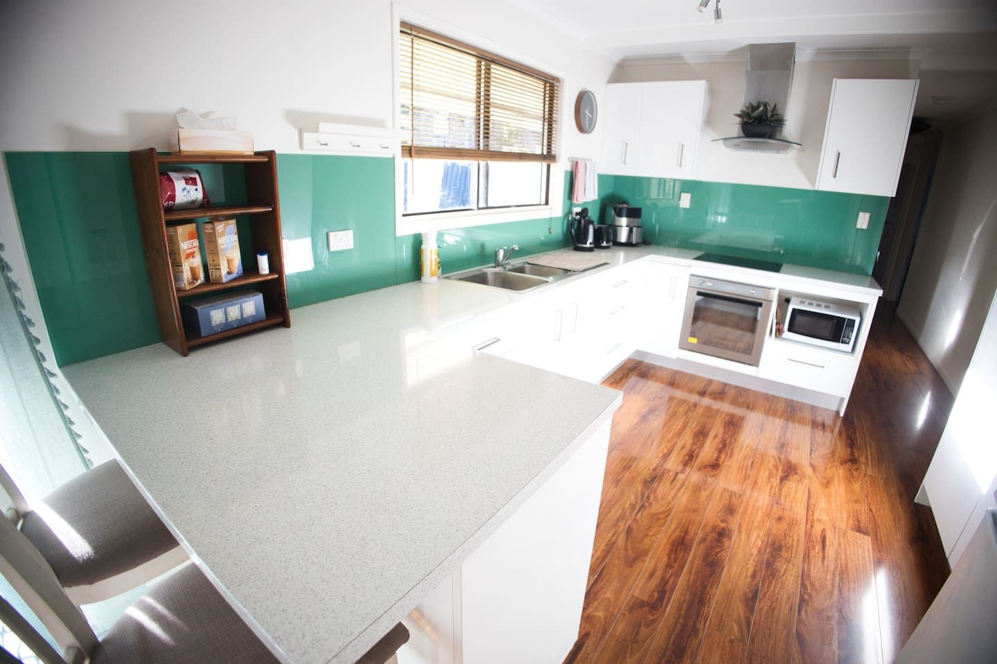 A kitchen with white cabinets, a wooden countertop, a sink, a stove, and a microwave.