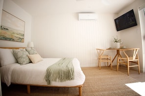 A bedroom with a bed, bedside table, chairs, a TV, and a painting on the wall. - Private-Pool Studio in Currumbin (Currumbin)