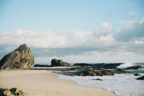 A beach with a large rock formation, sandy shore, and waves. - Private-Pool Studio in Currumbin (Currumbin)