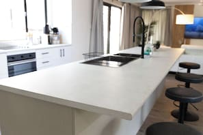 Een moderne keuken met een groot schiereiland, barkrukken en een hanglamp.
