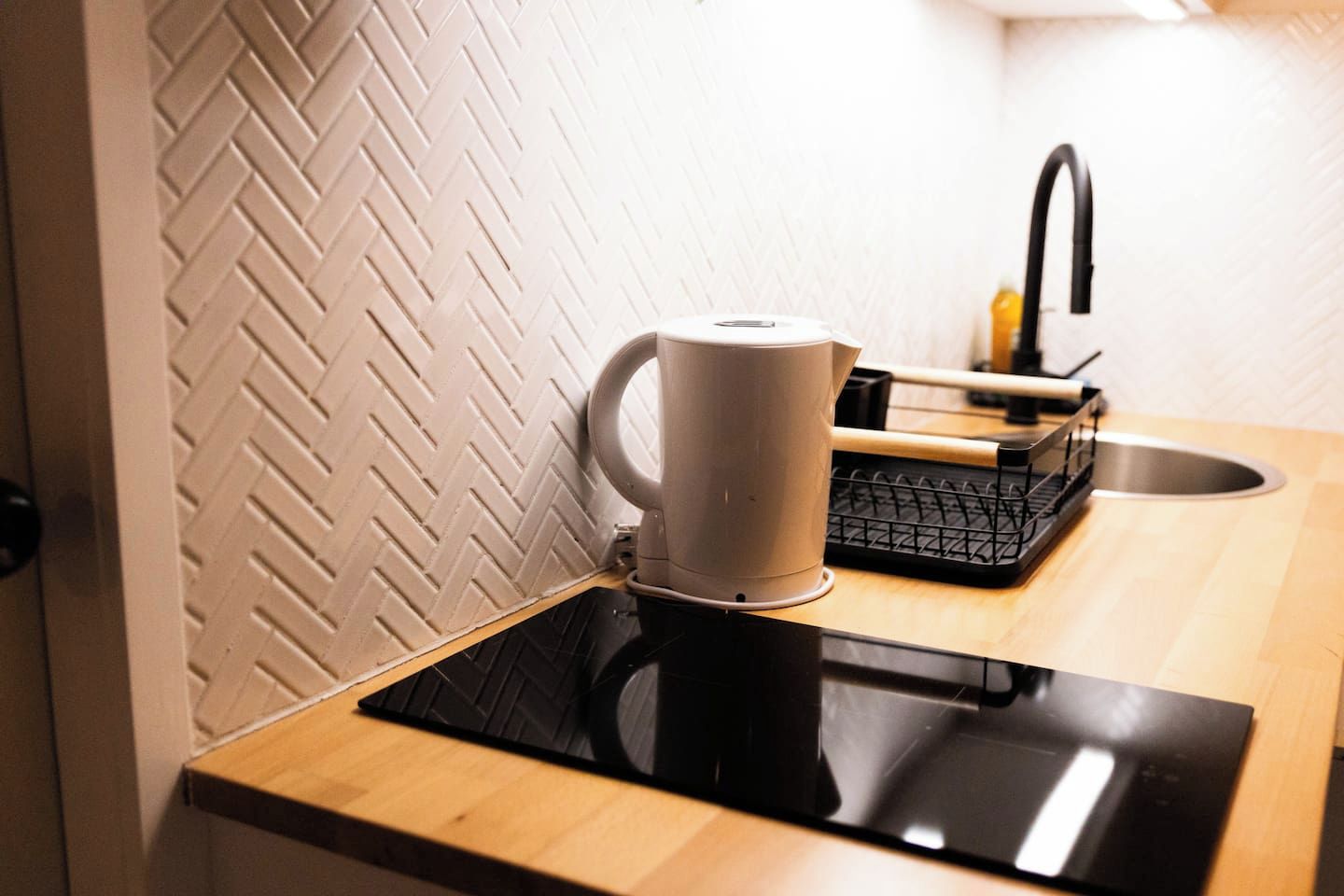 A kitchen with a coffee maker on the counter, a sink, and a black tray.
