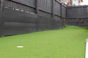 A fenced backyard with artificial green turf and a white circular object. - Convenient and Peaceful Studio in Brisbane South (Shailer Park)