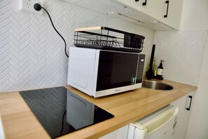 Una cocina pequeña equipada con microondas, un lavamanos y un refrigerador compacto.