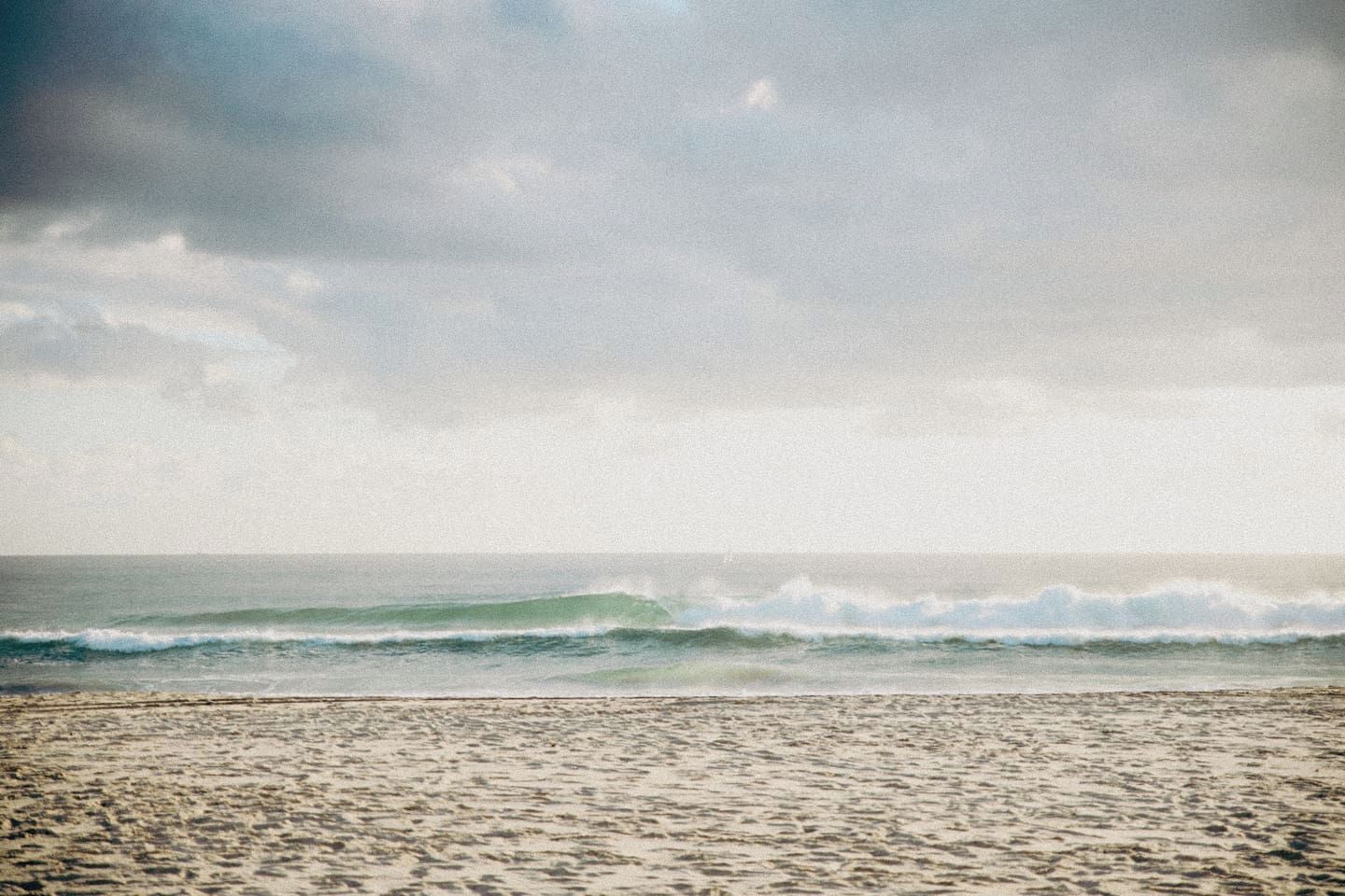 Une plage avec des vagues et un ciel nuageux.