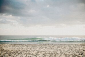 A beach with waves and a cloudy sky.