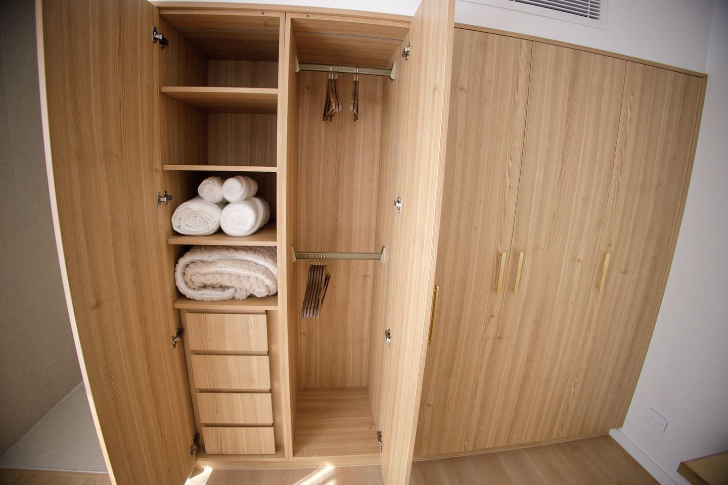 Un armadio in legno con ripiani multipli e spazio per appendere, probabilmente utilizzato per riporre abiti e accessori.