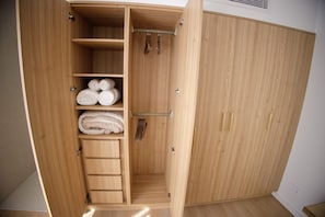 Une armoire en bois dotée de plusieurs étagères et d’un espace pour suspendre des vêtements, probablement utilisée pour ranger des vêtements et des accessoires.