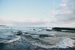 A beach with waves crashing onto rocks and a distant shoreline.