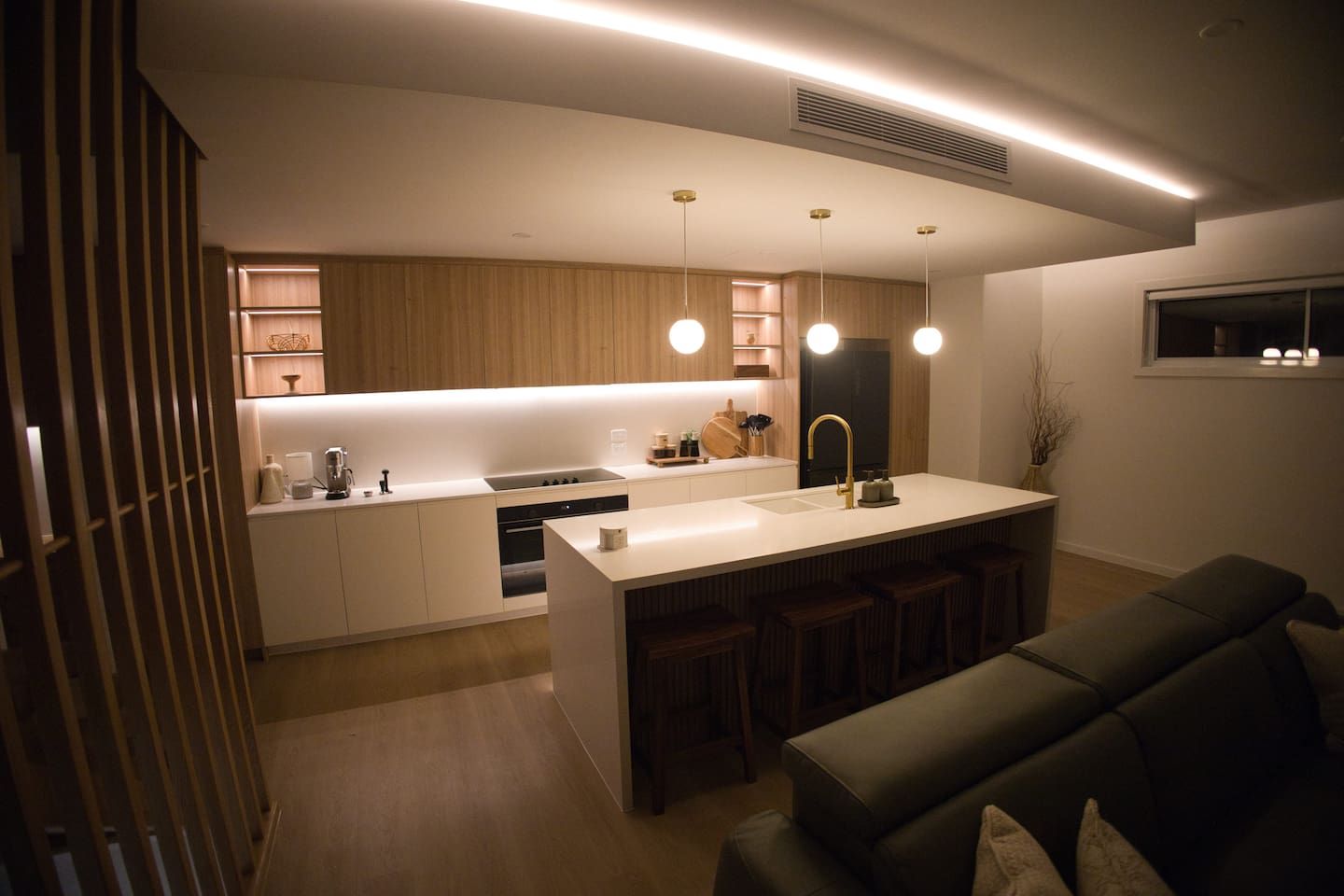 Una cucina moderna con isola centrale, illuminazione a sospensione e piano cottura integrato.