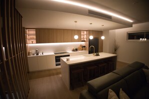 Une cuisine moderne dotée d’un îlot central, de luminaires suspendus et d’une cuisinière intégrée.