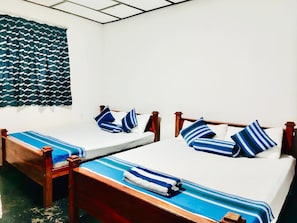 A room with two wooden beds, each with a blue-striped bedspread and matching pillows. - Green Haven Anuradhapura (Anuradhapura)