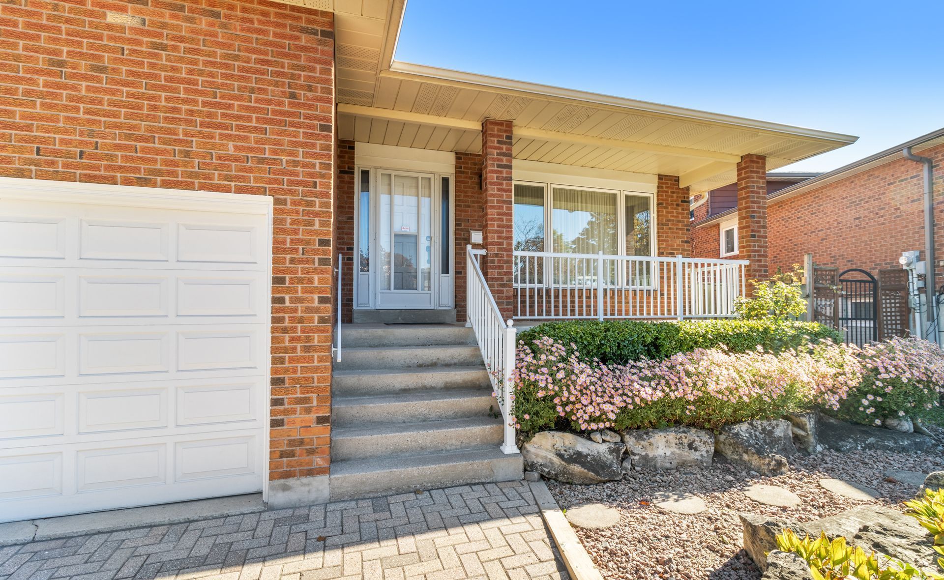 Charming brick entry with covered porch, garage, and lovely landscaping