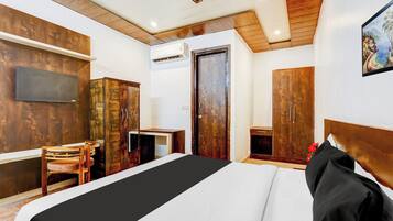 Ein Hotelzimmer mit einem Bett, einem Schreibtisch, einem Stuhl, einem Kleiderschrank und einem Fernseher an der Wand.