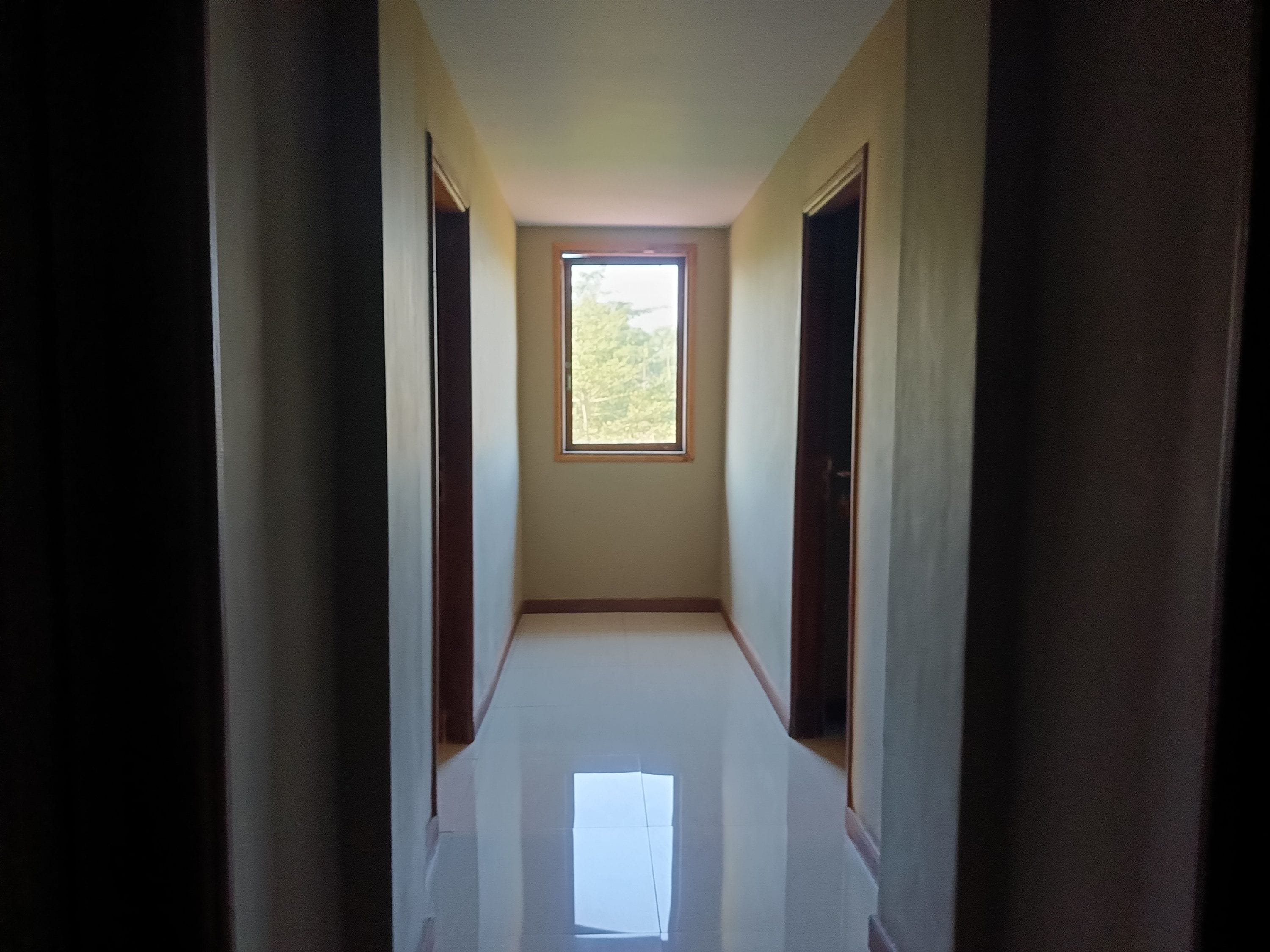 Un estrecho pasillo con una ventana al final, que conduce a una habitación.