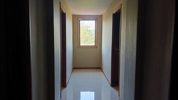 Un estrecho pasillo con una ventana al final, que conduce a una habitación.