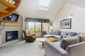 A living room with a fireplace, a sofa set, a recliner, a coffee table, and a TV mounted on the wall. - 2BR at Nordic Village w/ shared pool, game room near ski, golf & storyland (Bartlett)