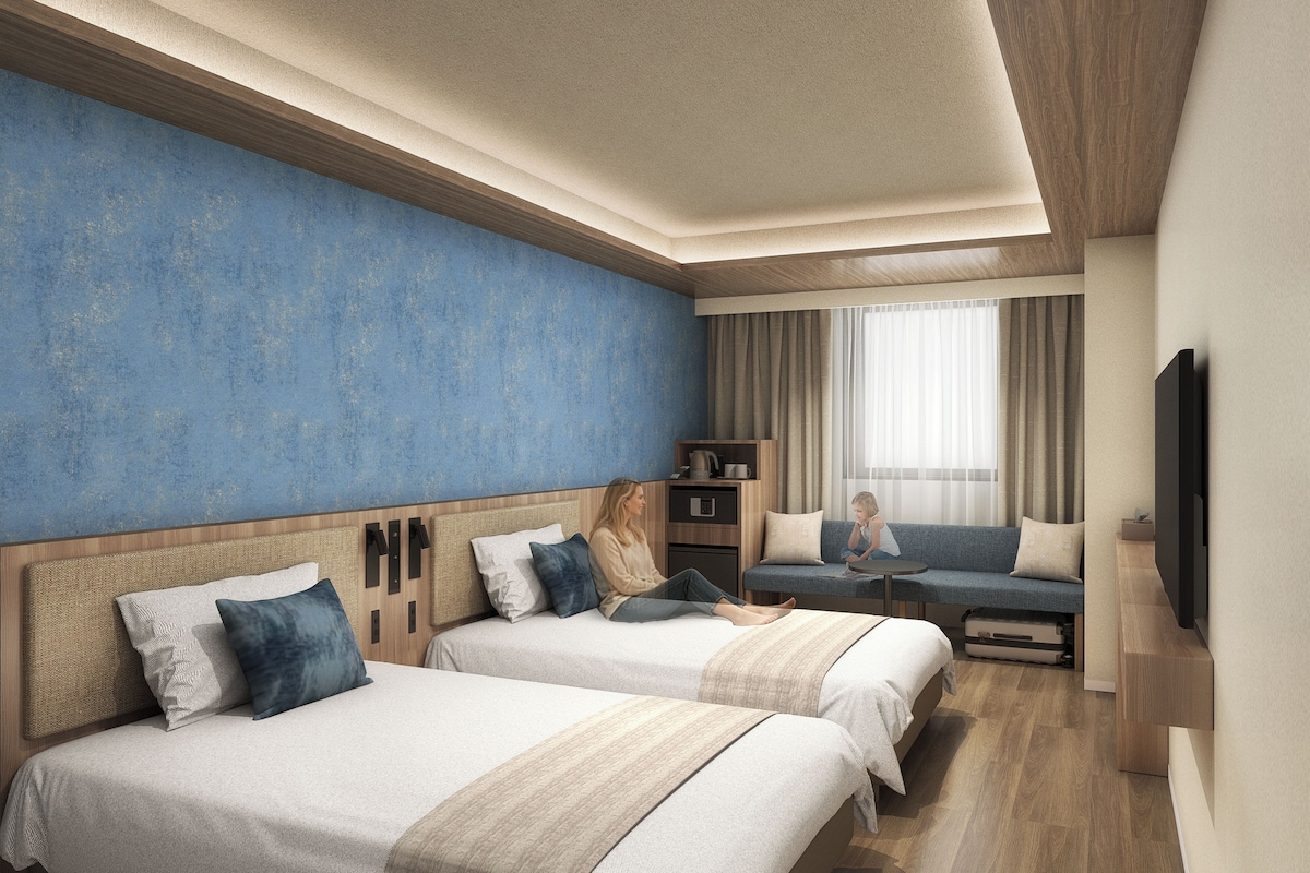 Habitación de hotel con dos camas, un sofá, un televisor y una ventana con cortinas.