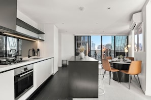 Una cucina moderna con isola centrale, zona pranzo con sedie e ampie finestre che offrono vista sulla città.