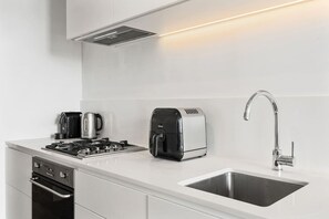 Eine moderne Küche mit Gasherd, Kaffeemaschine, Toaster und Spüle aus Edelstahl.