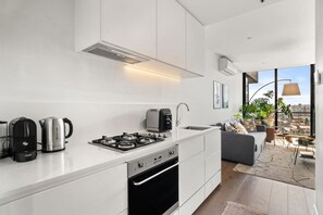 A modern kitchen with a gas stove, coffee maker, and kettle. - Green 1 Bedroom by Flagstaff (West Melbourne)
