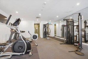 A gym with cardio equipment, weight machines, and a mirror wall. - Green 1 Bedroom by Flagstaff (West Melbourne)