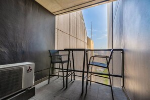 A balcony with a Mitsubishi air conditioner, two chairs, and a metal fence. - Cozy 1 Bedroom by Flagstaff (Melbourne)