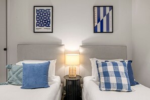 A hotel room with two beds, each with a pillow and a framed artwork above. - Lovely 2 Bedroom with Parking (Docklands)