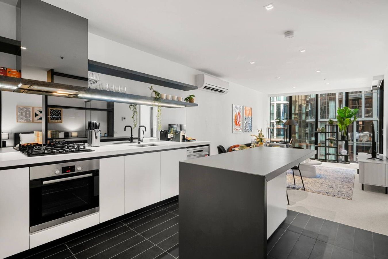 A modern kitchen with a central island, built-in appliances, and a large window overlooking a cityscape.