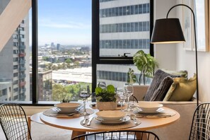 A dining area with a table set for four, a city view, and a large window. - Central 2 Bedroom with Sauna (Melbourne)