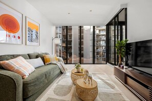 A modern living room with a sofa, coffee table, and a TV. - Chic 2 Bedroom near Marvel (Docklands)