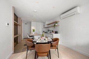 A modern kitchen with built-in appliances, a dining area with a round table and chairs, and a visible door leading to another room. - Chic 2 Bedroom near Marvel (Docklands)