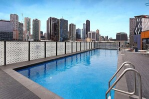 A rooftop pool with a city skyline view, surrounded by high-rise buildings. - Gorgeous 2 Bedroom by Marvel (Docklands)