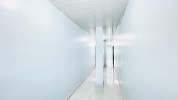 A long, narrow hallway with white walls and a tiled floor.