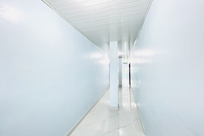 A long, narrow hallway with white walls and a tiled floor.