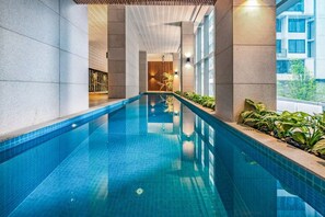 Una piscina interior con agua cristalina, rodeada de paredes y plantas.