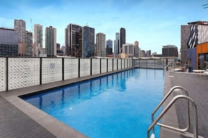 A rooftop pool with a city skyline view, surrounded by high-rise buildings. - Marvel Stadium View 2 Bedroom (Docklands)