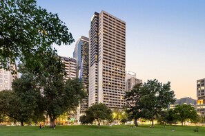 A park with trees and a large building with multiple floors and balconies. - Cozy Flagstaff Studio with Gym (Melbourne)