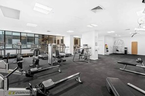 Et fitnesscenter med varieret træningsudstyr, herunder løbebånd, styrkemaskiner og håndvægte.