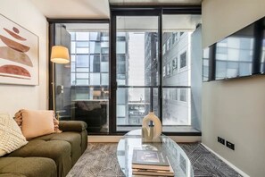 Ein modernes Wohnzimmer mit einer Couch, einem Glastisch und einer Stehlampe.