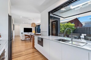 A modern kitchen with a large island, a built-in oven, and a window overlooking a garden. - Palm Beach Oasis a comfortable three-bedroom townhouse (Palm Beach)