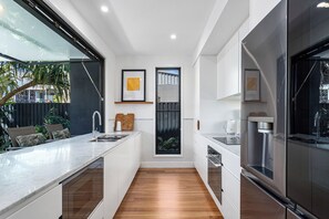 A modern kitchen with a marble countertop, stainless steel appliances, and a wooden floor. - Palm Beach Oasis a comfortable three-bedroom townhouse (Palm Beach)