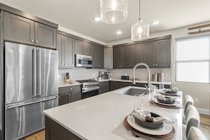 A modern kitchen with stainless steel appliances, a large island, and pendant lighting. - Newly Renovated! 3-Bed with Free Shuttle, Free Ski Waxes + Grill (Daniel)