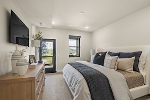 A bedroom with a bed, bedside table, lamp, and a TV mounted on the wall. - Newly Renovated! 3-Bed with Free Shuttle, Free Ski Waxes + Grill (Daniel)