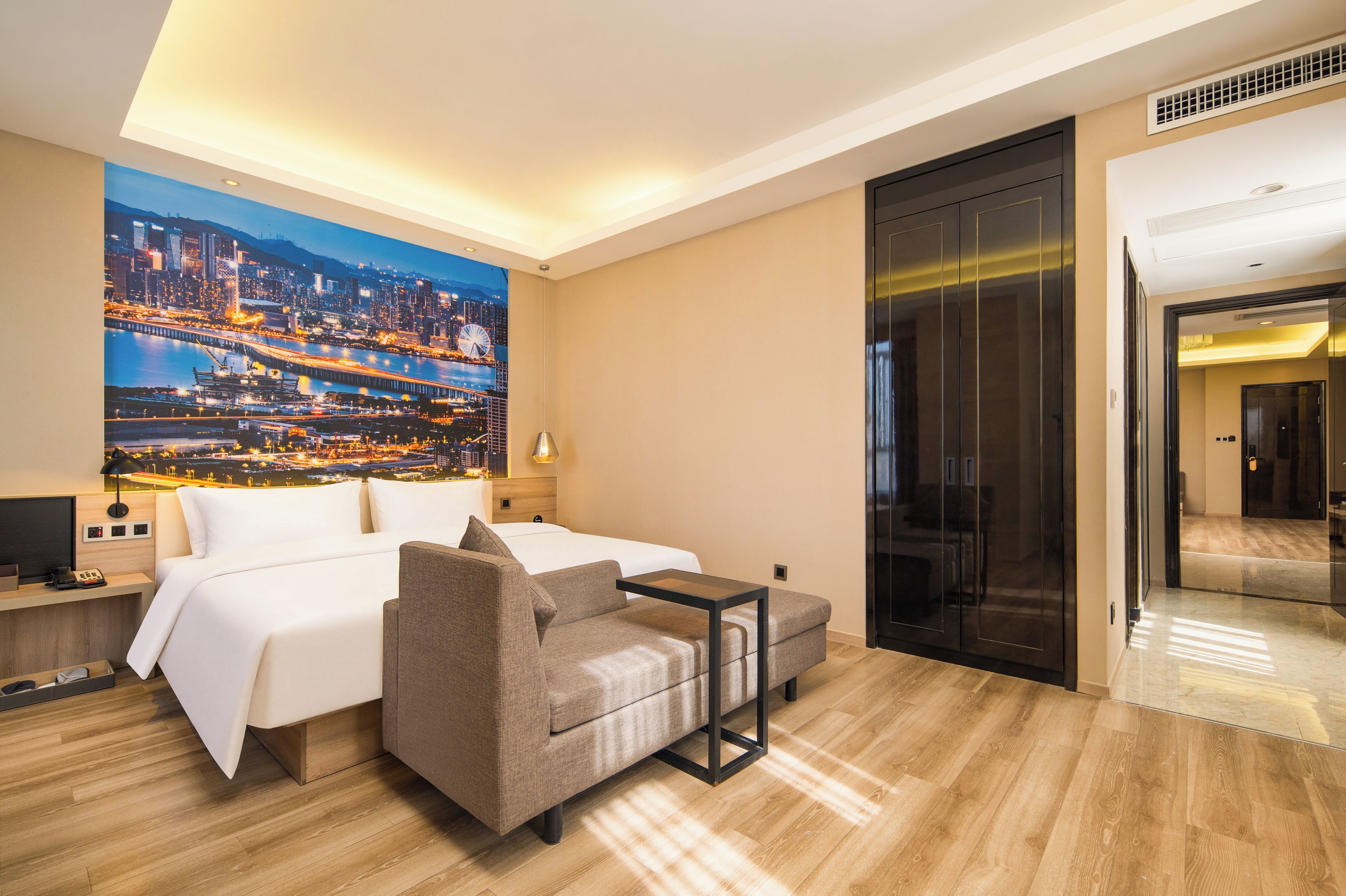 Una camera d'albergo con un letto, un divano, una scrivania e vista sulla città.